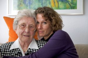Daughter with her arms around her elderly mother