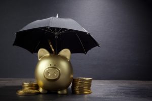 Gold Piggy bank with umbrella representing financial protection