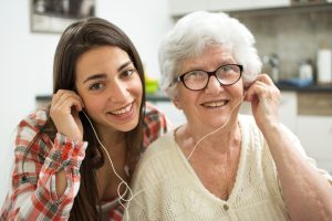 Teen and elderly woman sharing earpods.